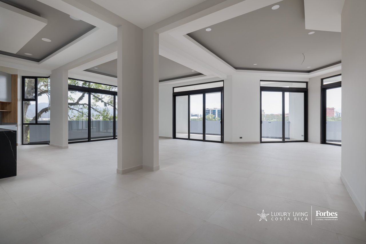 Vacant apartment living area with recessed ceilings and wide sliding glass doors to a balcony.