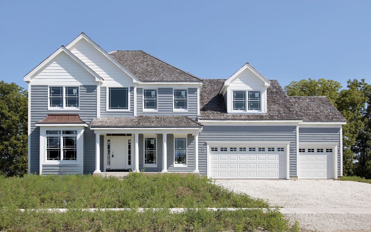 Two-story gray house with white trim, multiple gables, a covered entry, and an attached two-car garage.