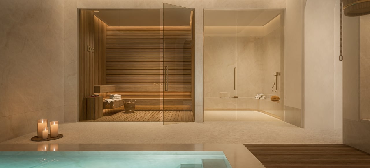 Spa with a glass-enclosed wooden sauna, walk-in shower, and pool edge.