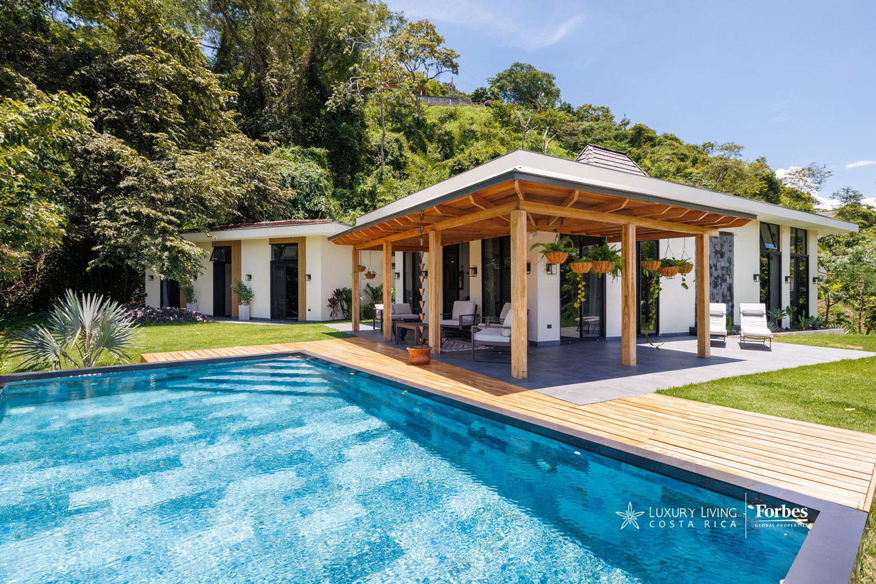 Modern home with a timber-covered patio beside a turquoise pool and wooden deck.