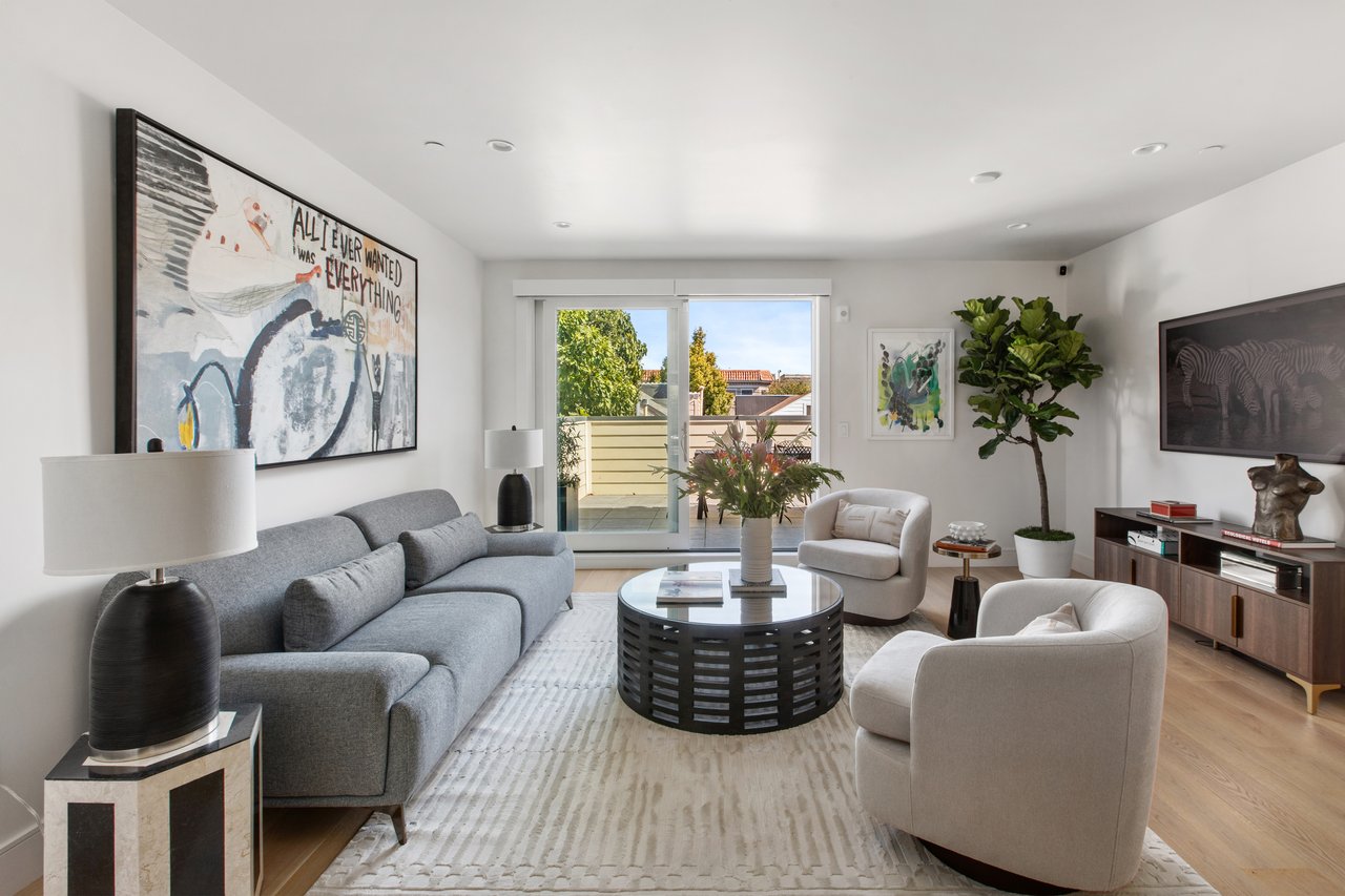 Living room with gray sofa, round coffee table, and sliding doors opening to a terrace.