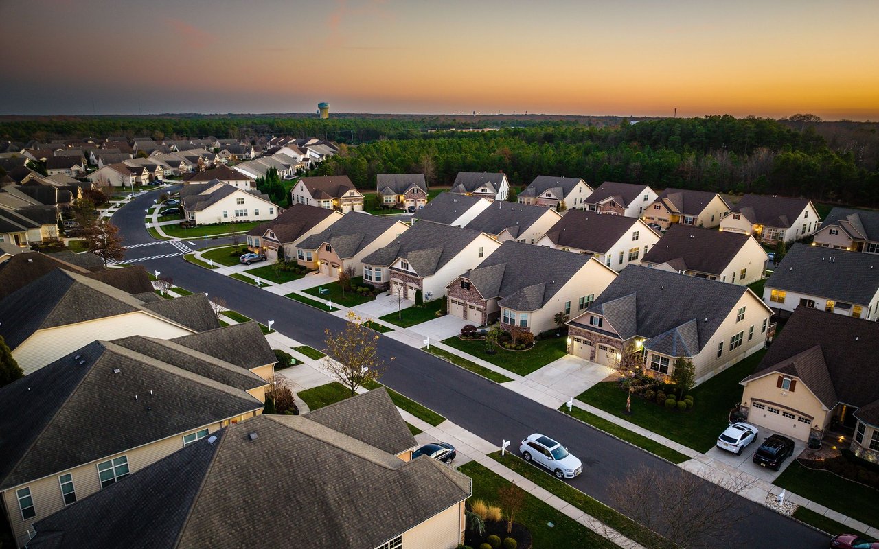 Aerial view of a residential neighborhood at sunset, with detached homes along a curving street.