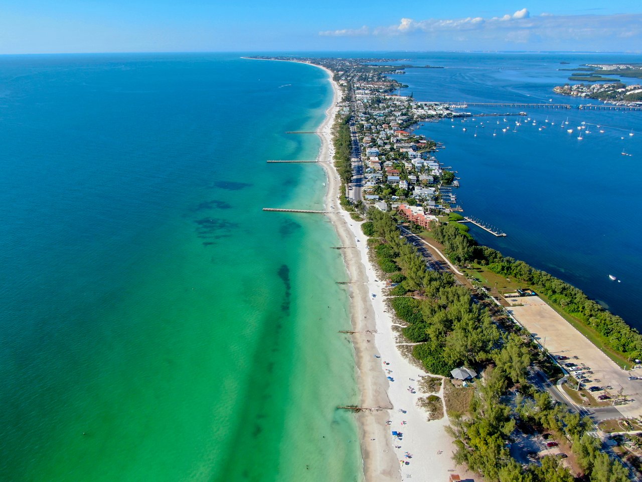 Coquina Sands coastline with a long Gulf beach, waterfront homes, and boats in the bay.