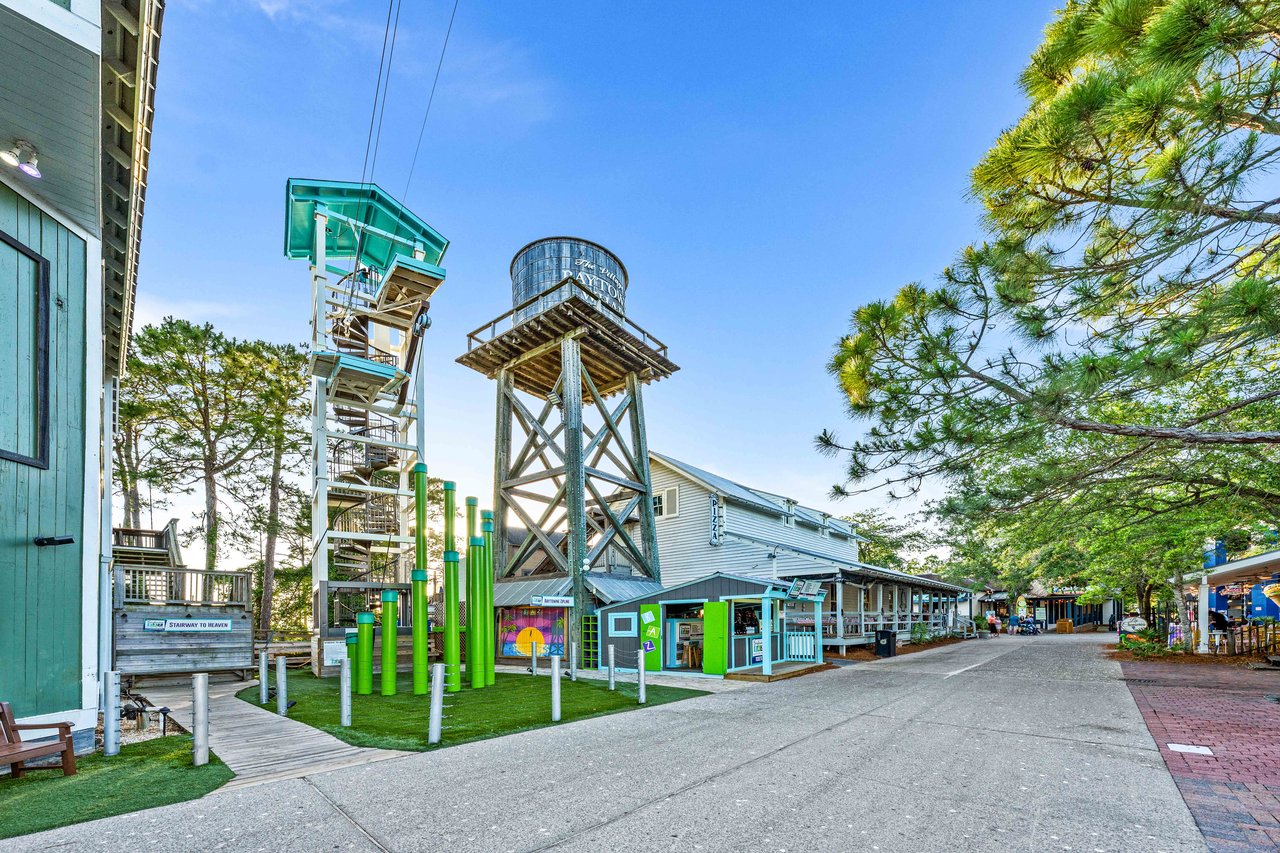 Baytowne Wharf village at Sandestin with the zipline tower and colorful storefronts along a brick pedestrian lane in Miramar Beach, Florida