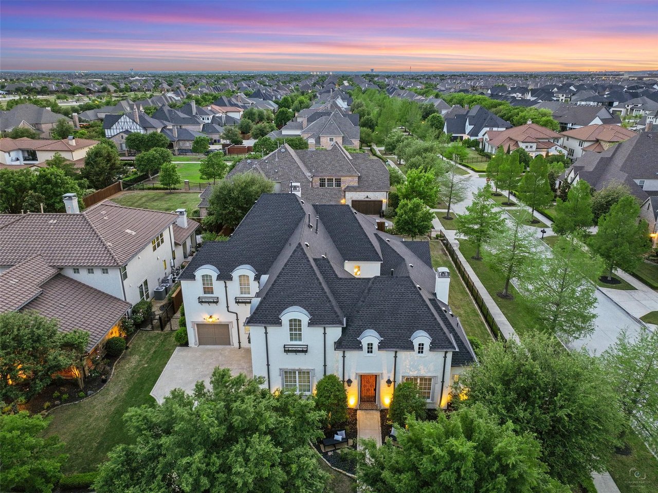Dusk aerial view of a stunning custom luxury home in Newman Village Frisco TX with manicured landscaping and expansive lot.