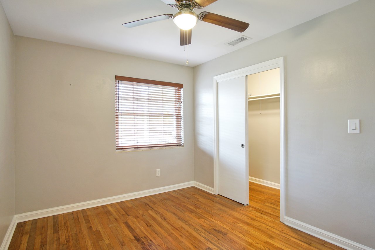 An empty room featuring hardwood floors and a ceiling fan, creating a spacious and airy atmosphere.