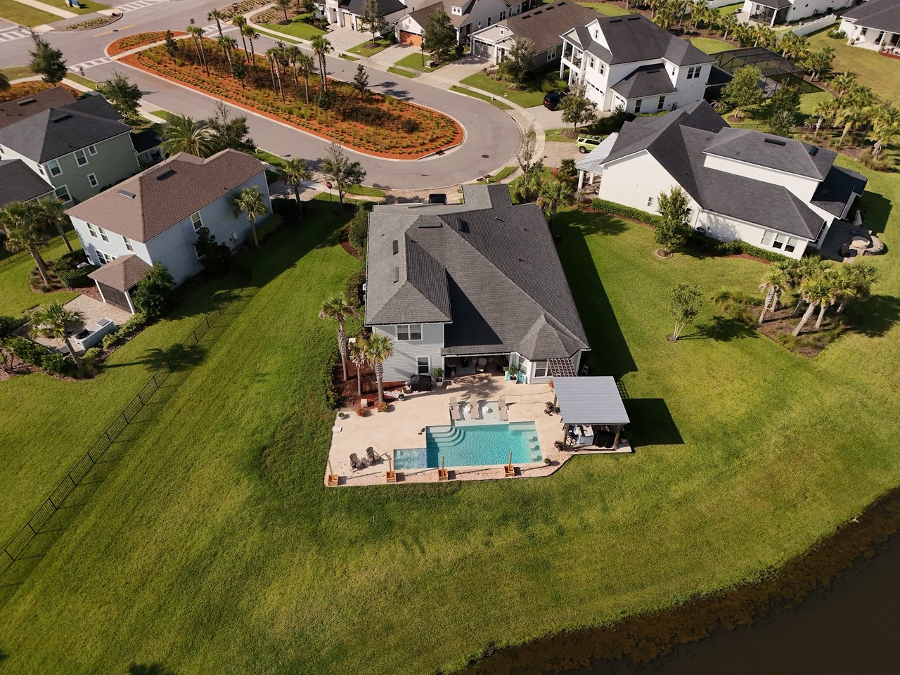 Aerial view of a Silverleaf Village home with a backyard pool beside a waterway.