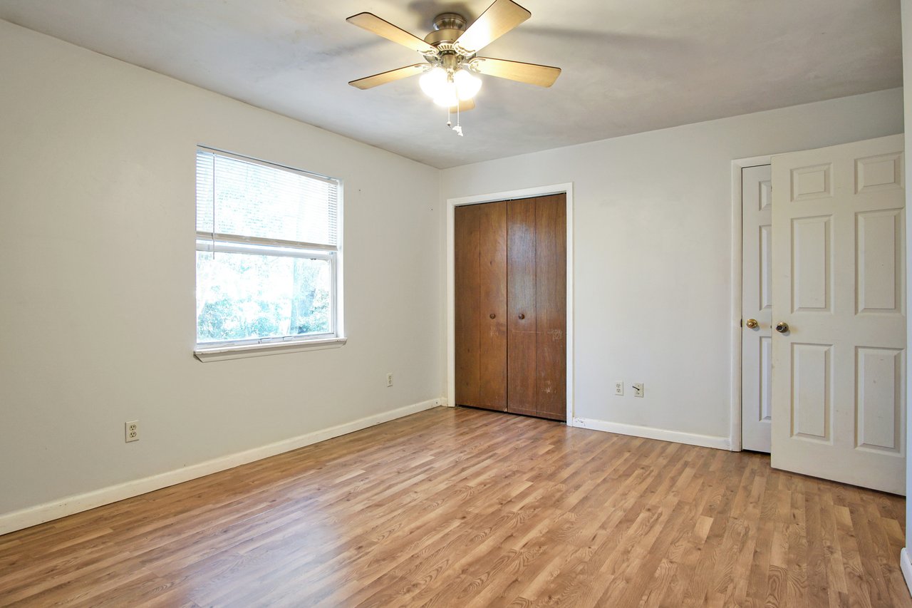 Empty room featuring hardwood floors and a ceiling fan, creating a spacious and airy atmosphere.