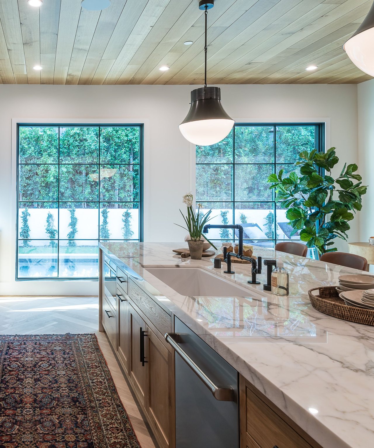 Modern kitchen with a marble island and large garden-facing windows.