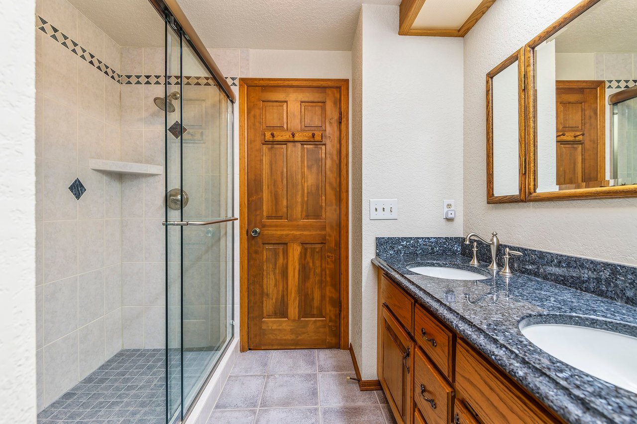 The upstairs bath is designed for both convenience and luxury, featuring double sinks for busy mornings and a tiled shower with dual shower heads, creating a spa-like experience in the comfort of your own home.