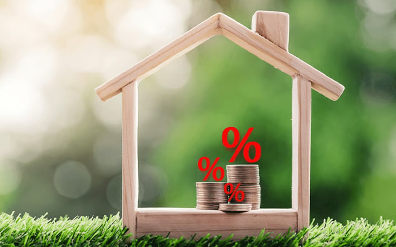 Wooden model house framing stacks of coins with red percent symbols.