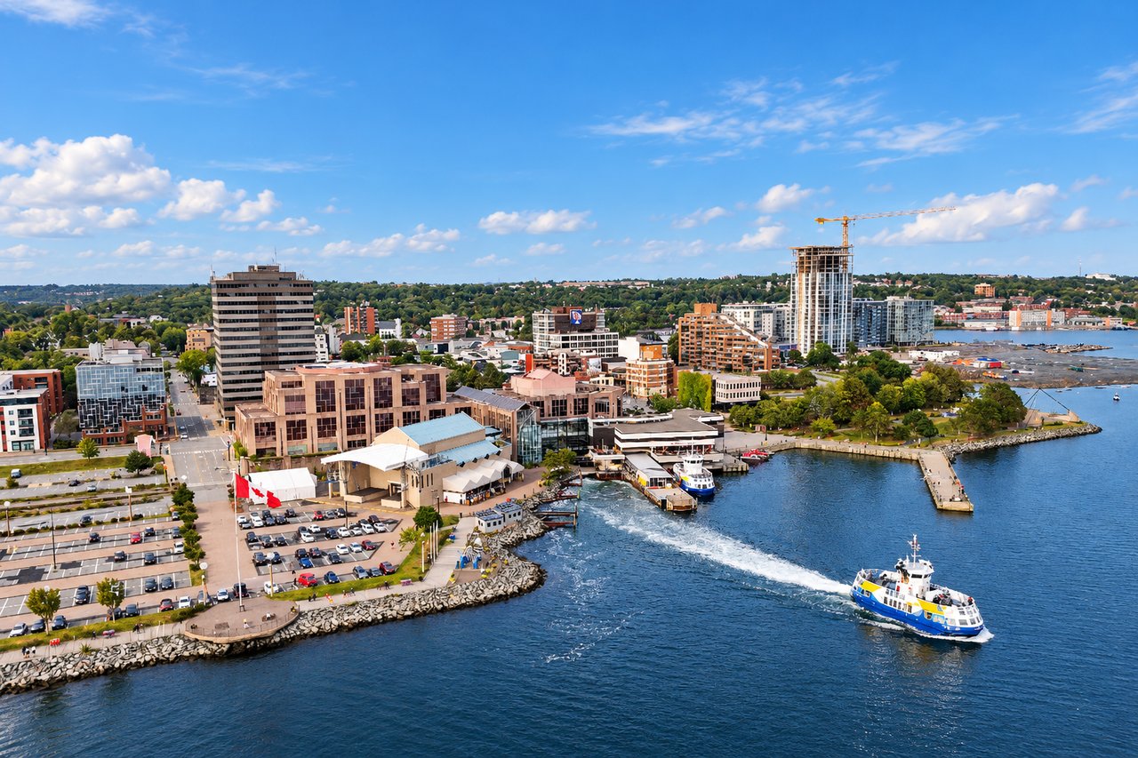 Dartmouth waterfront with downtown buildings and a ferry crossing the harbor.