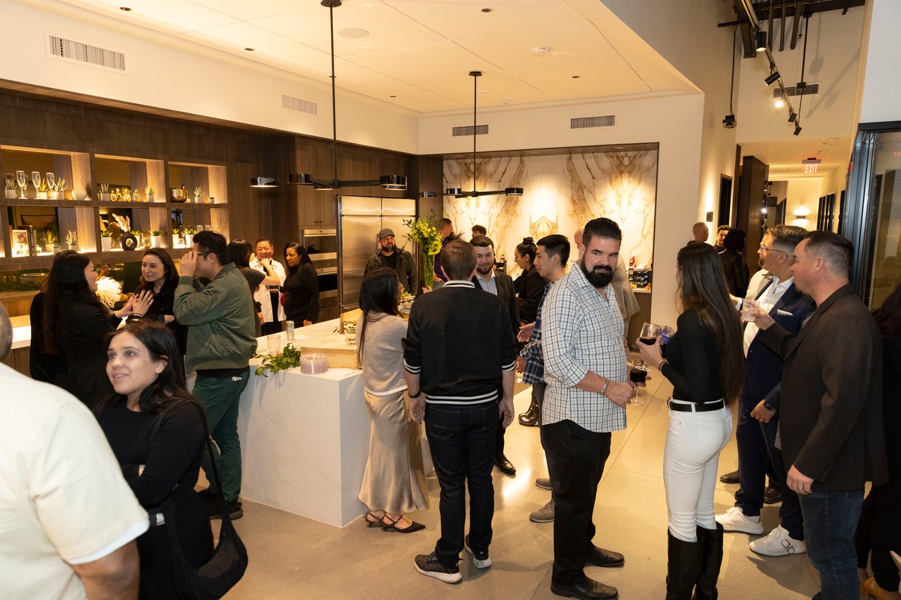 Guests mingle around a kitchen island at a client appreciation open house.