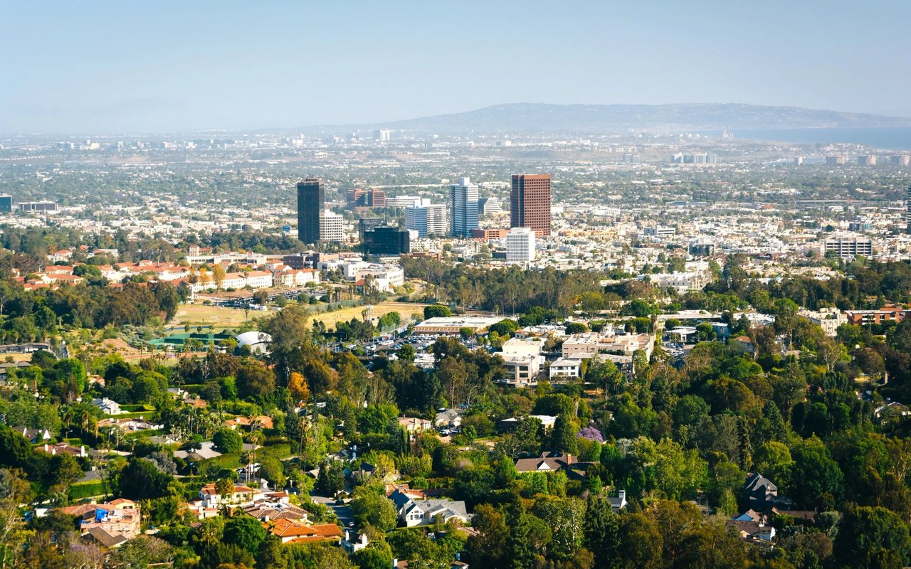 Panoramic city view with a cluster of high-rises beyond leafy residential streets.