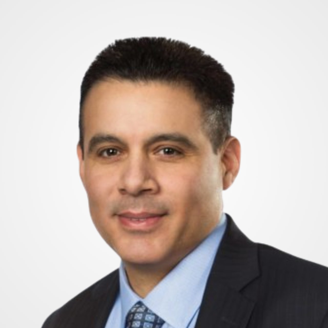James Callejas in a dark suit, light blue shirt, and patterned tie.