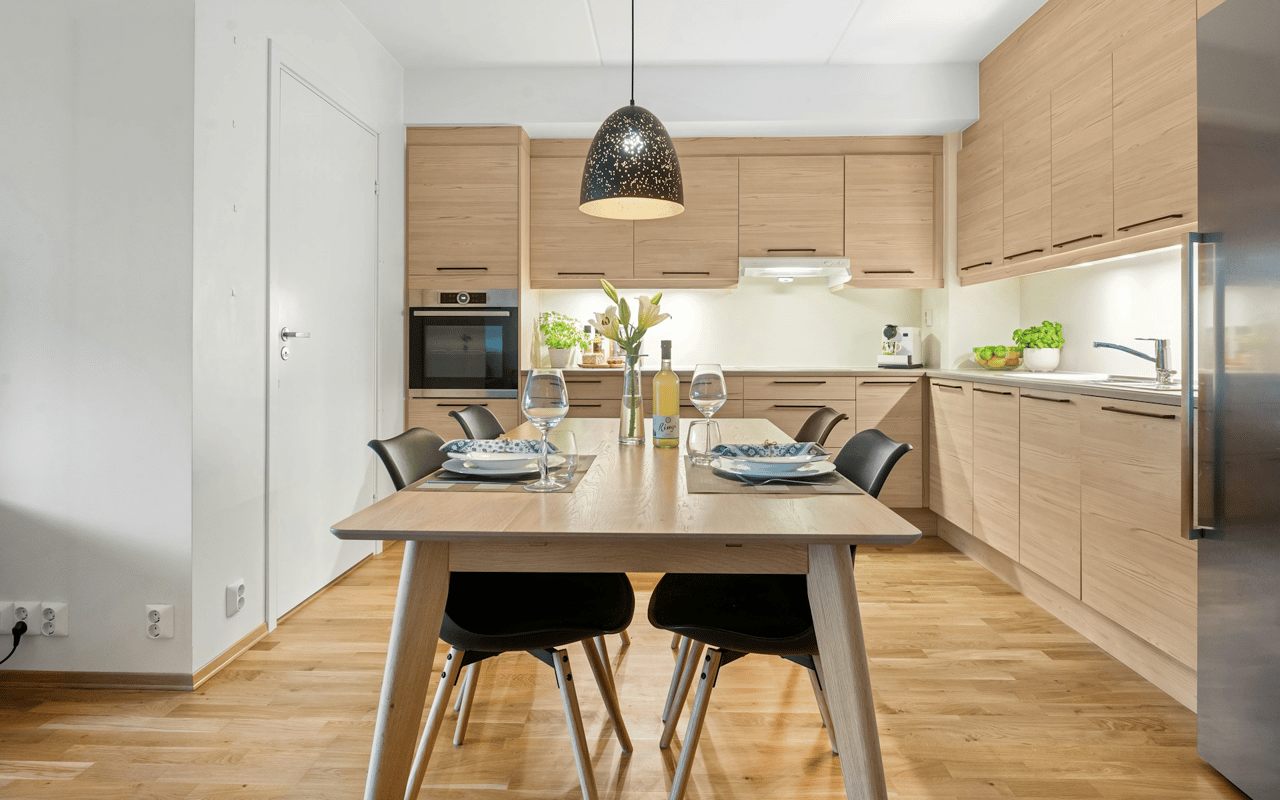 Modern kitchen with light wood cabinets and a dining table set for two.