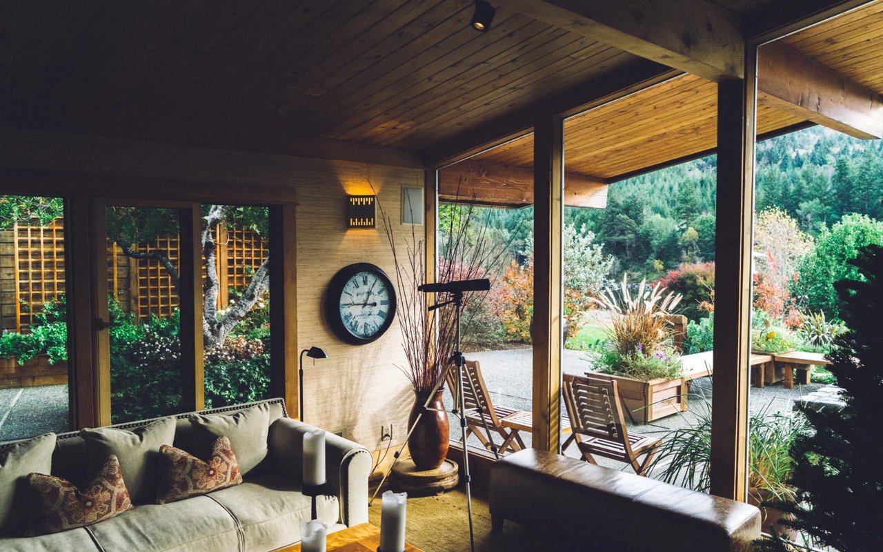 Living room with a wood-plank ceiling and large windows overlooking a landscaped garden.