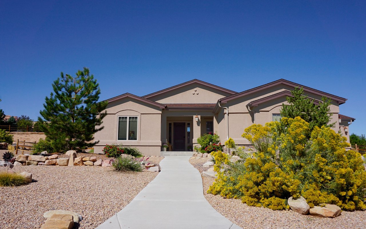 Single-story stucco home with a curved walkway and landscaped gravel front yard.