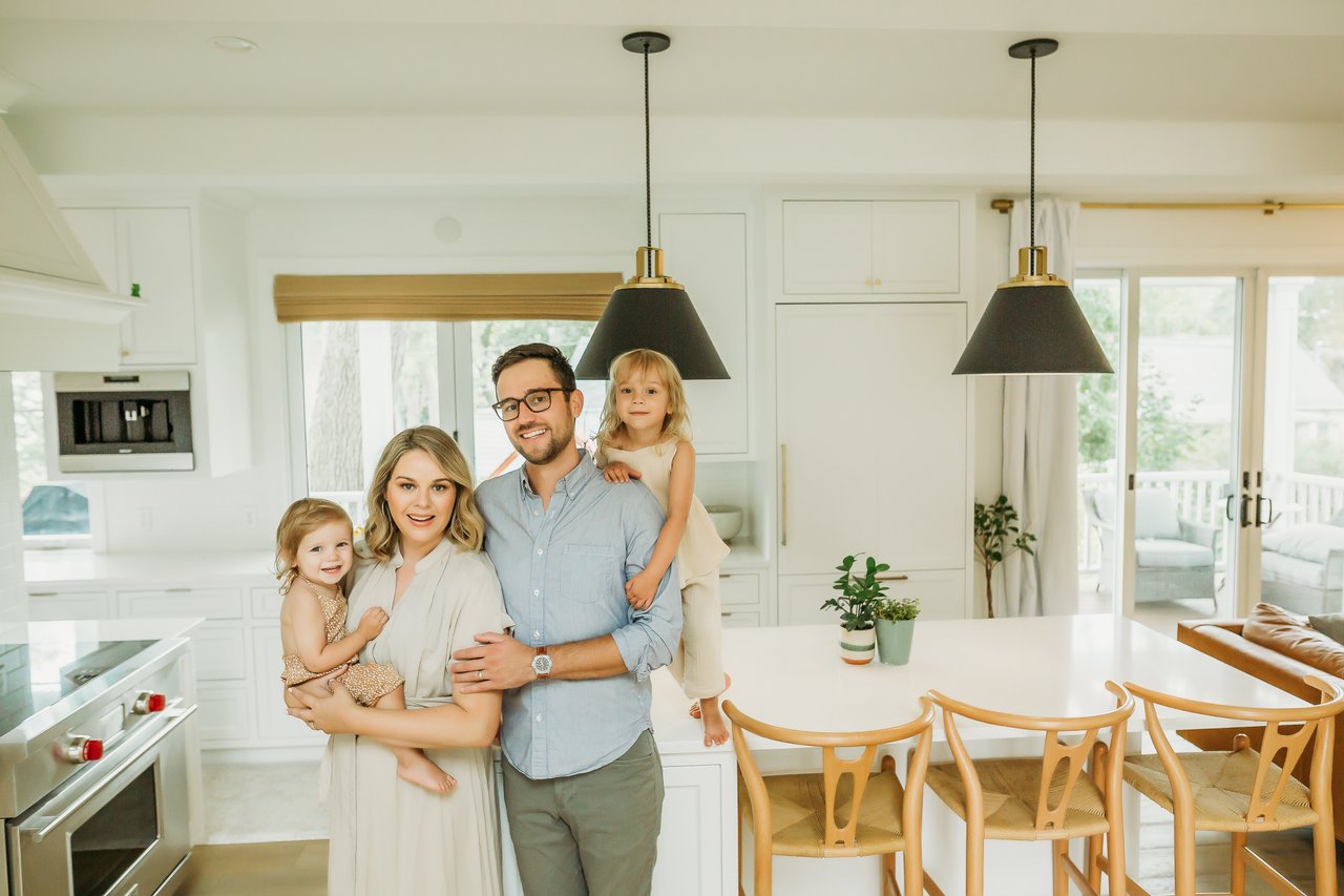 A happy family of four standing in their modern Madison, Wisconsin kitchen, representing the ideal lifestyle for parents searching for the best neighborhoods with top-rated schools in the Madison area.