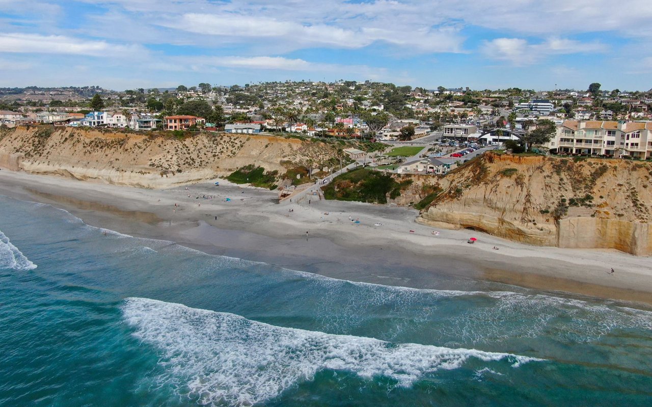 Solana Beach coastline with surf below sandy bluffs and homes along the shore.