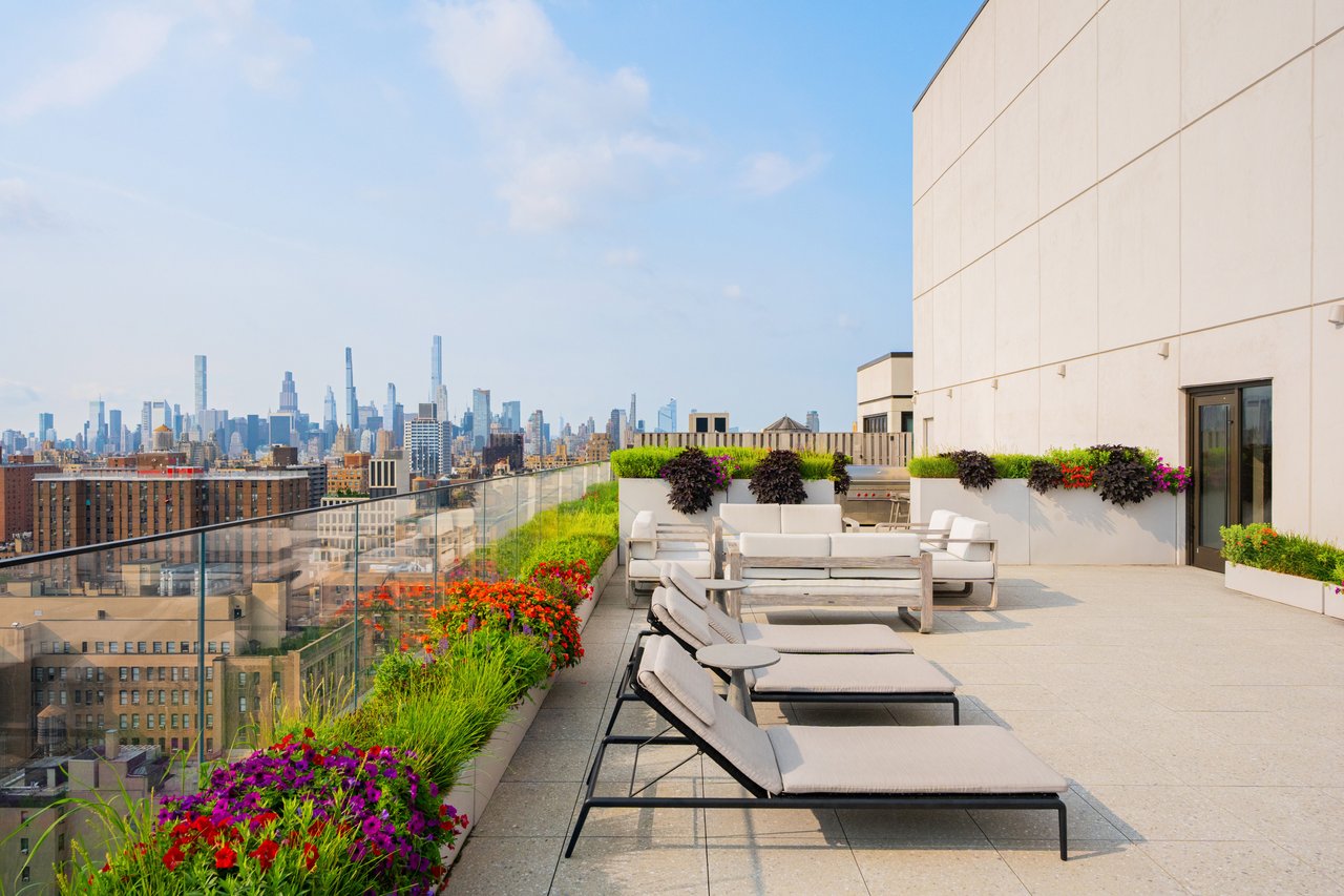 Rooftop terrace with lounge seating and flower beds overlooking the Manhattan skyline.