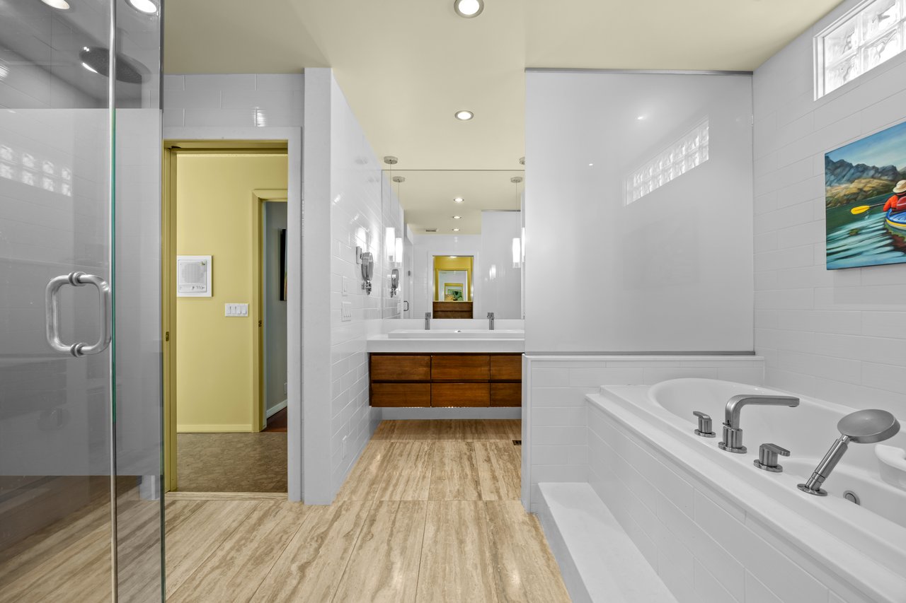 Modern bathroom with a built-in bathtub, glass shower, and wood-front double vanity.