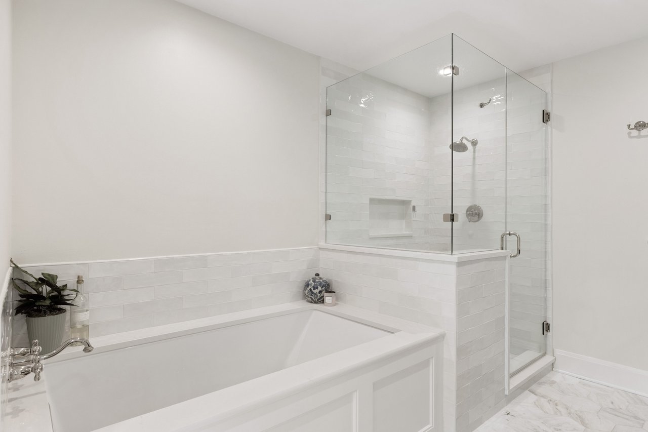 White bathroom with a built-in soaking tub beside a glass-enclosed shower.