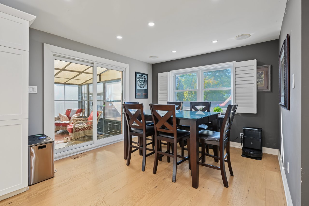 Dining room with a dark wood table beside sliding glass doors to an enclosed sunroom.