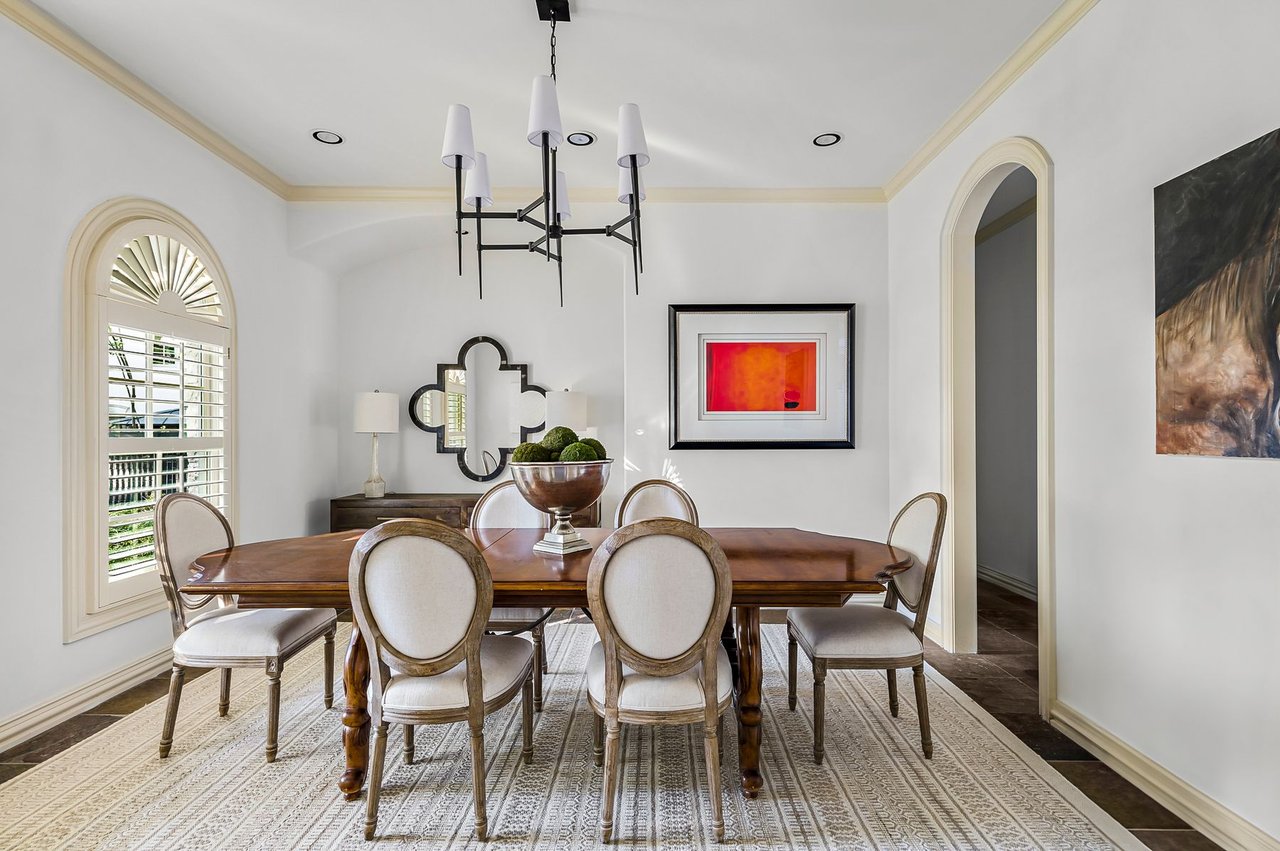 Formal dining room with wood table, upholstered chairs, and arched windows at 5902 Saratoga Cove, Davenport Ranch, Austin, Texas.