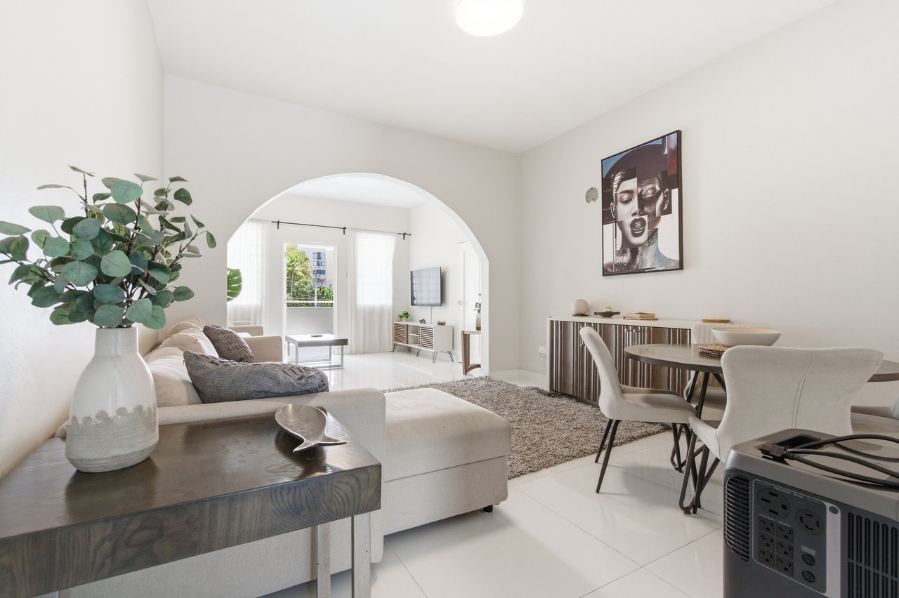 Furnished living and dining room with a large archway and neutral seating.