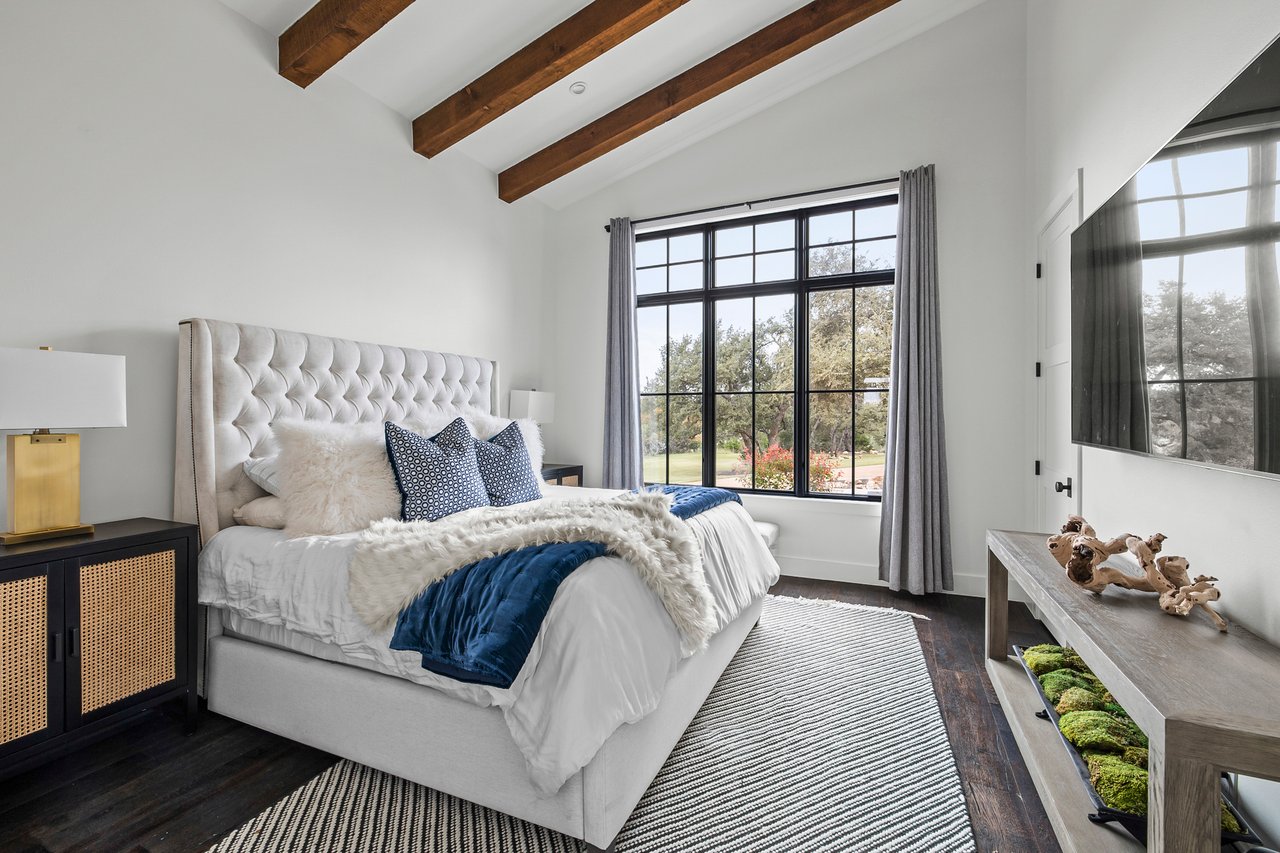 Guest bedroom with a vaulted, wood beamed ceiling in this Creek Road Ranch home in Dripping Springs, Texas.