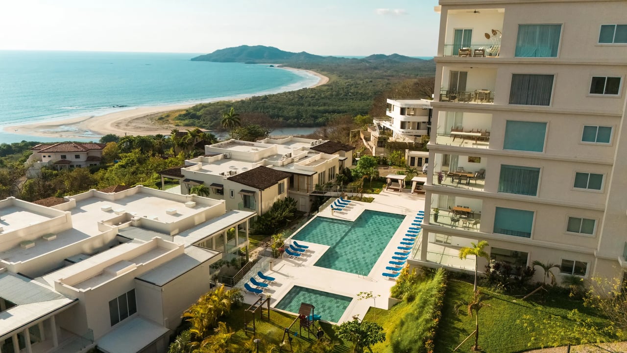 Residencia La Vista condos and swimming pools overlook Tamarindo's curved beach and ocean.