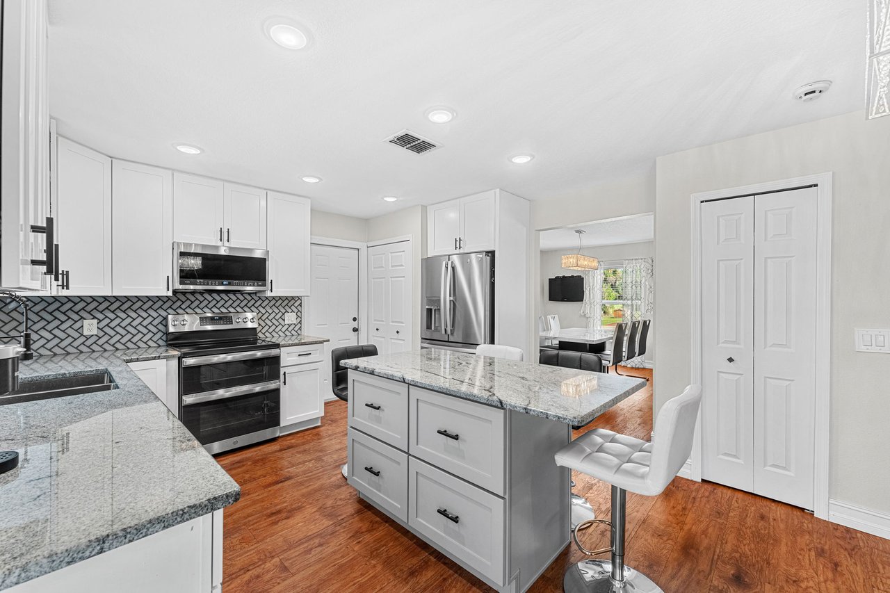Remodeled 2023 kitchen with white cabinetry and breakfast bar seating