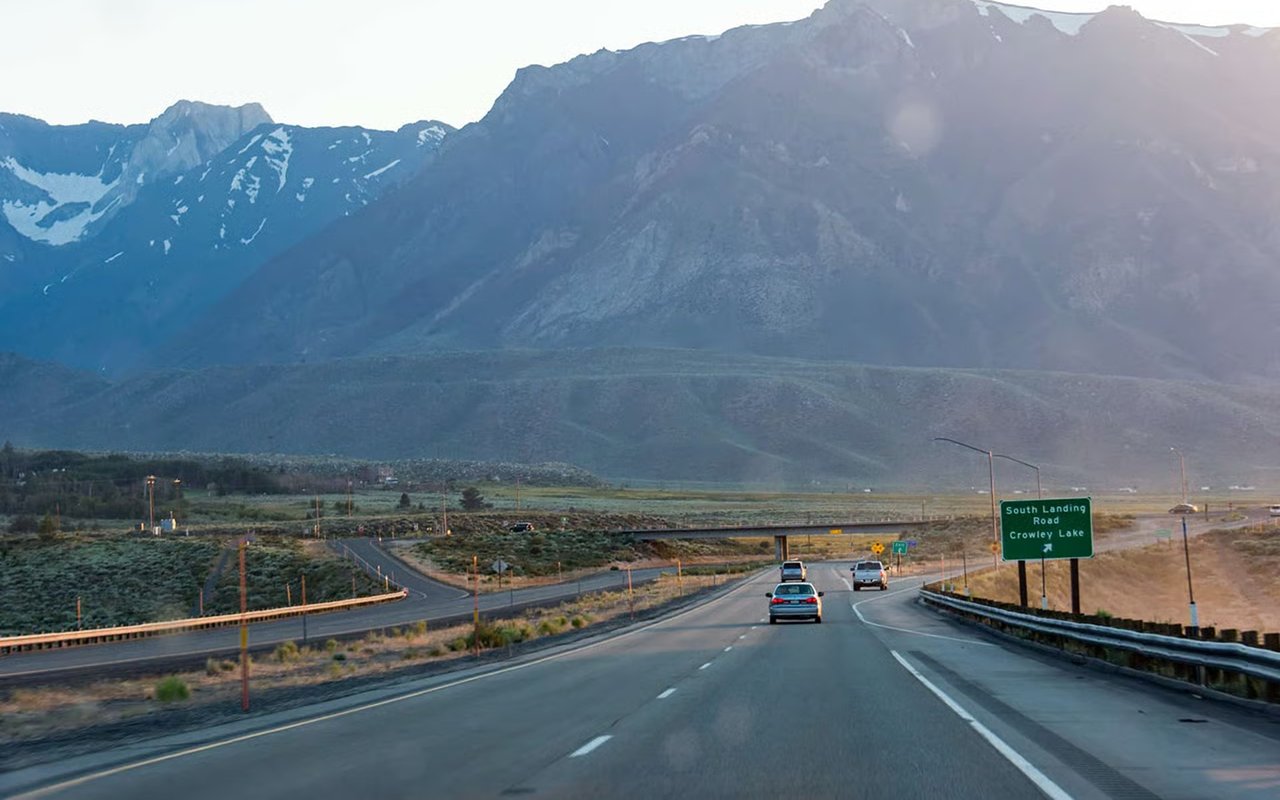 Highway sign for Crowley Lake beneath a sunlit mountain range.