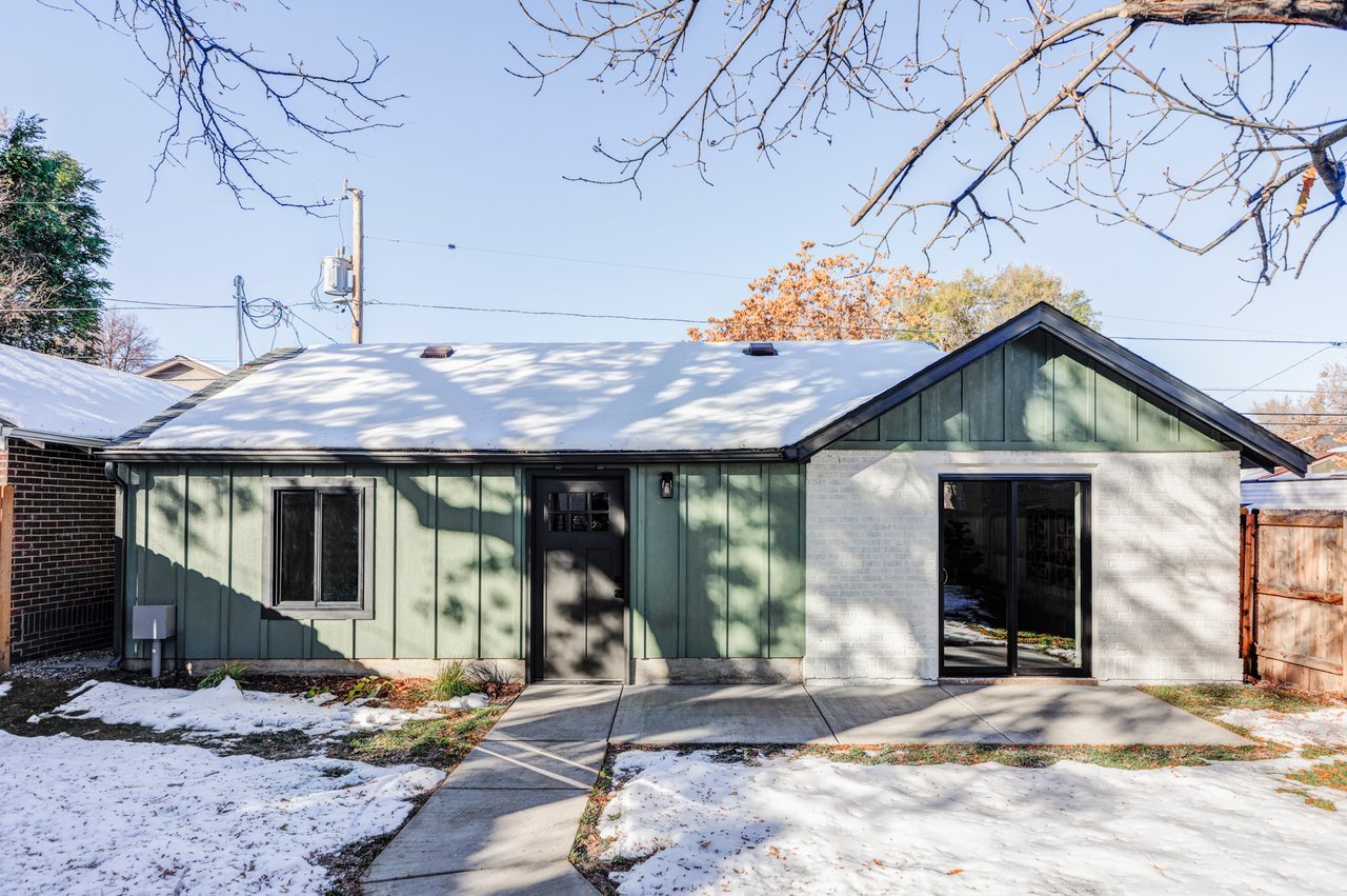 Green paneled detached garage with window and door, attached to a white brick ADU with a sliding glass door