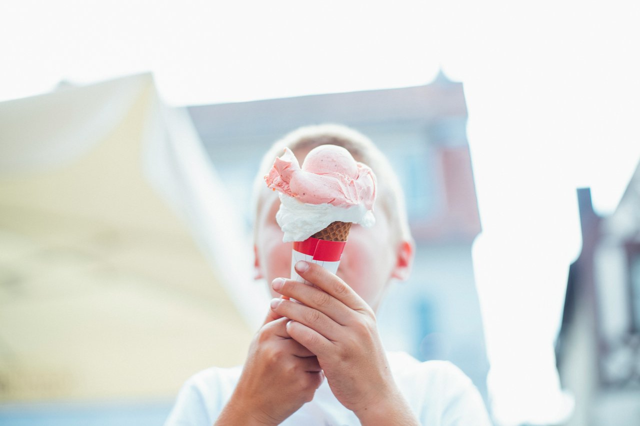 Child holding a pink-and-white ice cream cone outdoors