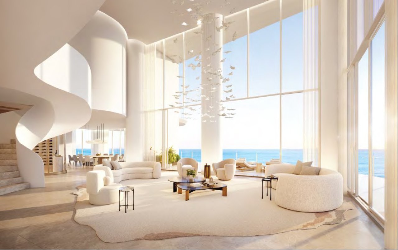 Double-height penthouse living room at The Ritz-Carlton Residences, South Beach with curved staircase, floor-to-ceiling windows, and panoramic ocean views.