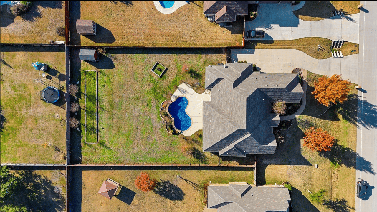 Aerial view of a Haslet TX home with private pool, large backyard, and 3-car driveway in a residential neighborhood.