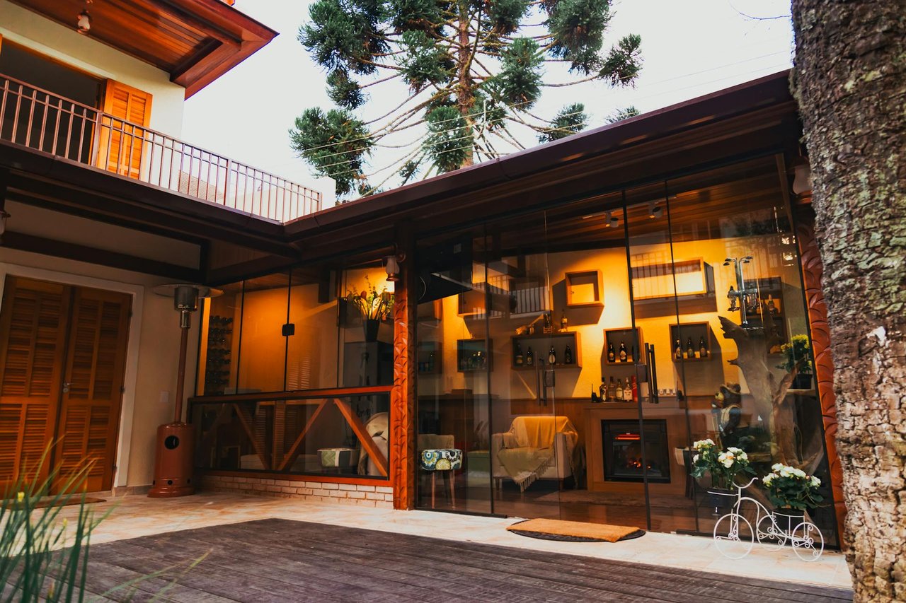 Luxury home outdoor living area with glass walls, warm interior lighting, and modern rustic design