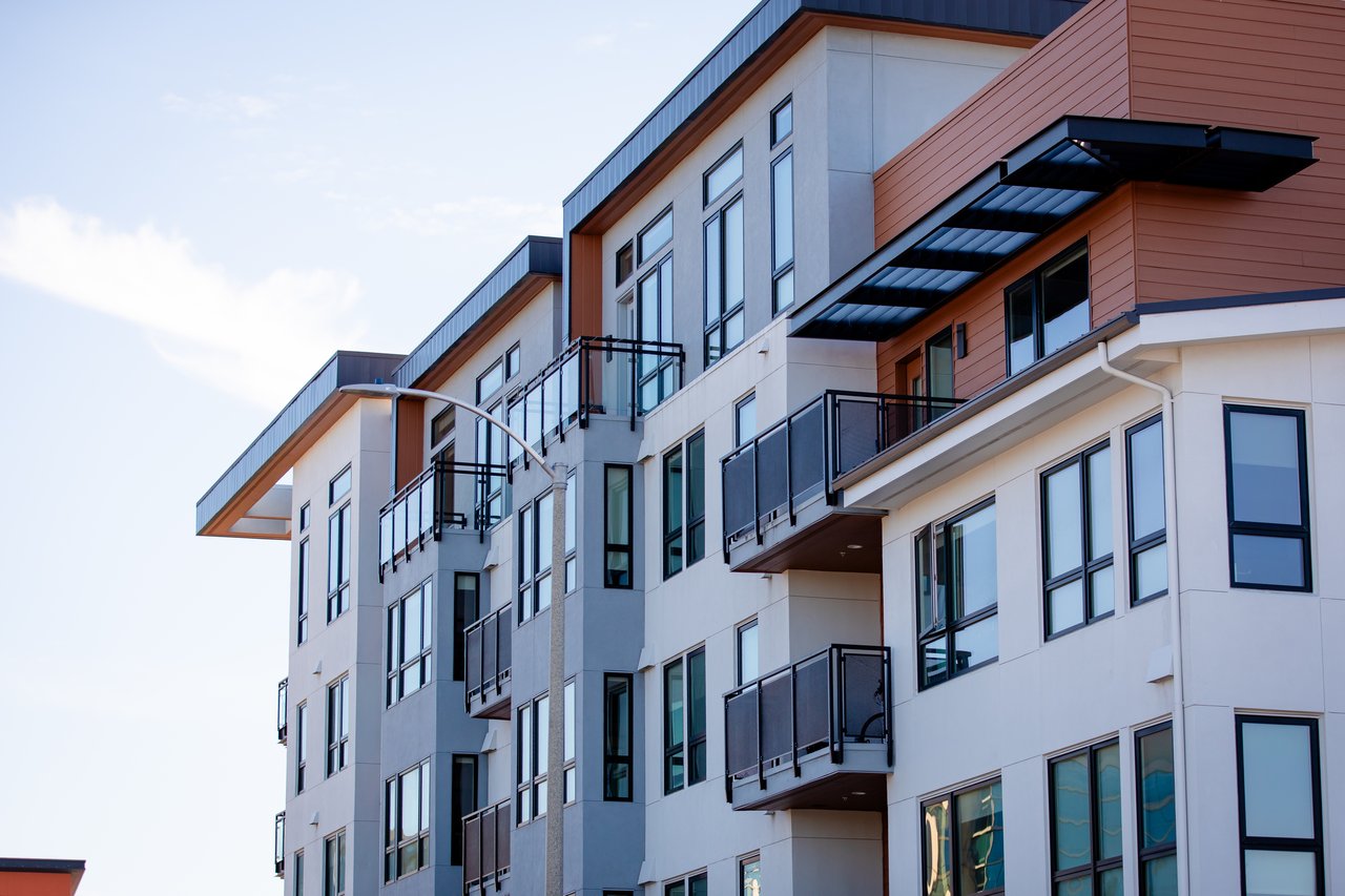 Modern condominium building with rust-colored siding and balconies with dark railings.