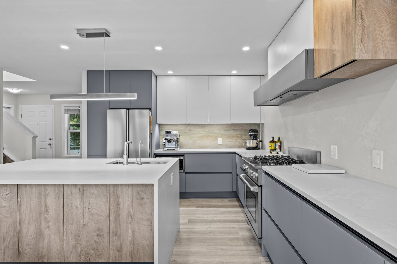 Modern kitchen with gray cabinets, a gas range, and a large wood-front island.