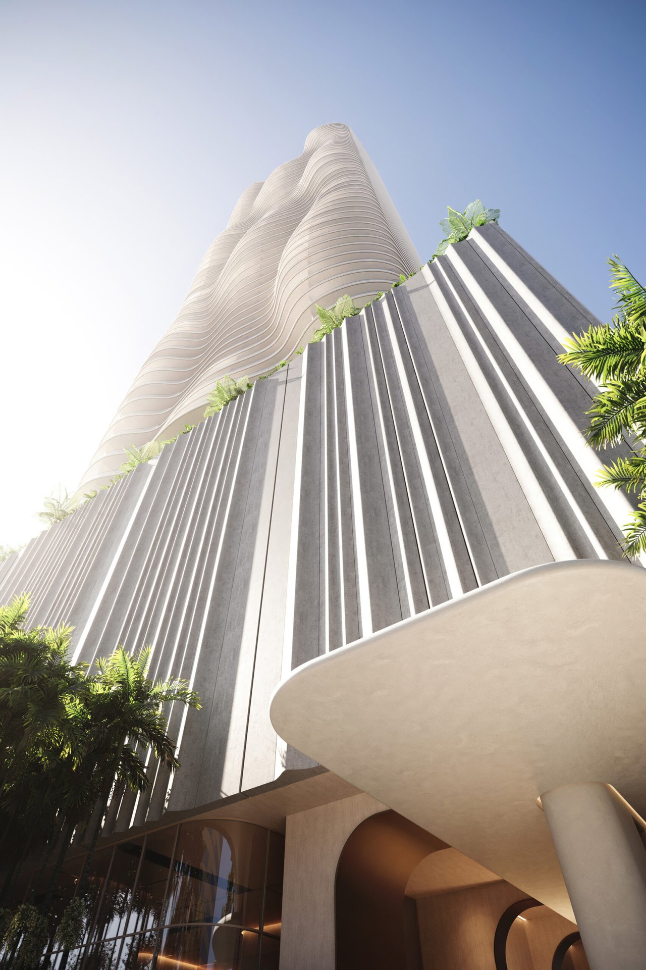 1428 Residences tower with an undulating white facade above a ribbed entrance and tropical landscaping.