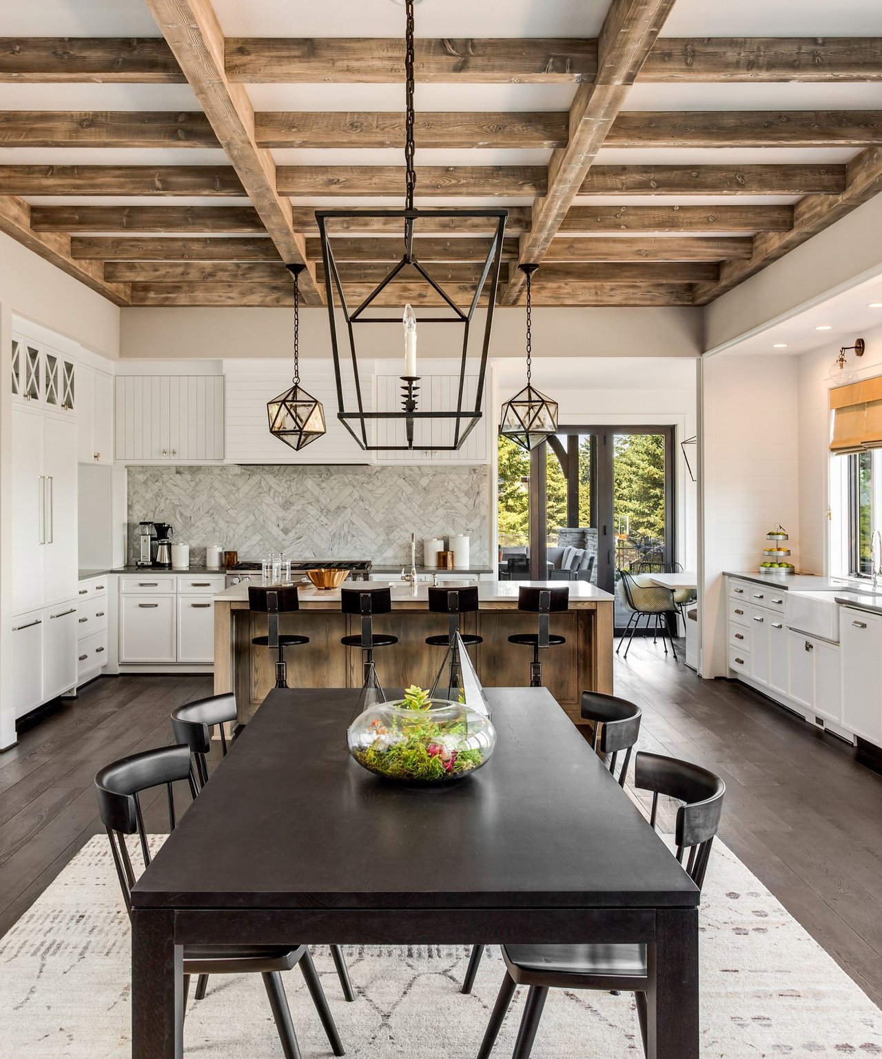 Bright kitchen and dining area with exposed timber beams, marble backsplash, and oversized island.