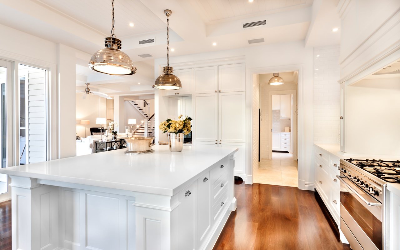 Luxurious kitchen with white island, pendant lights, and stainless steel appliances.