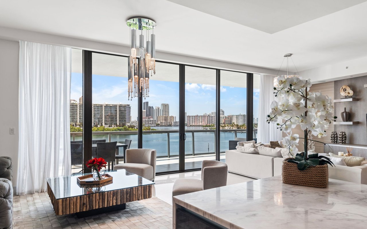 Modern condo living room with floor-to-ceiling windows overlooking the water and city skyline.