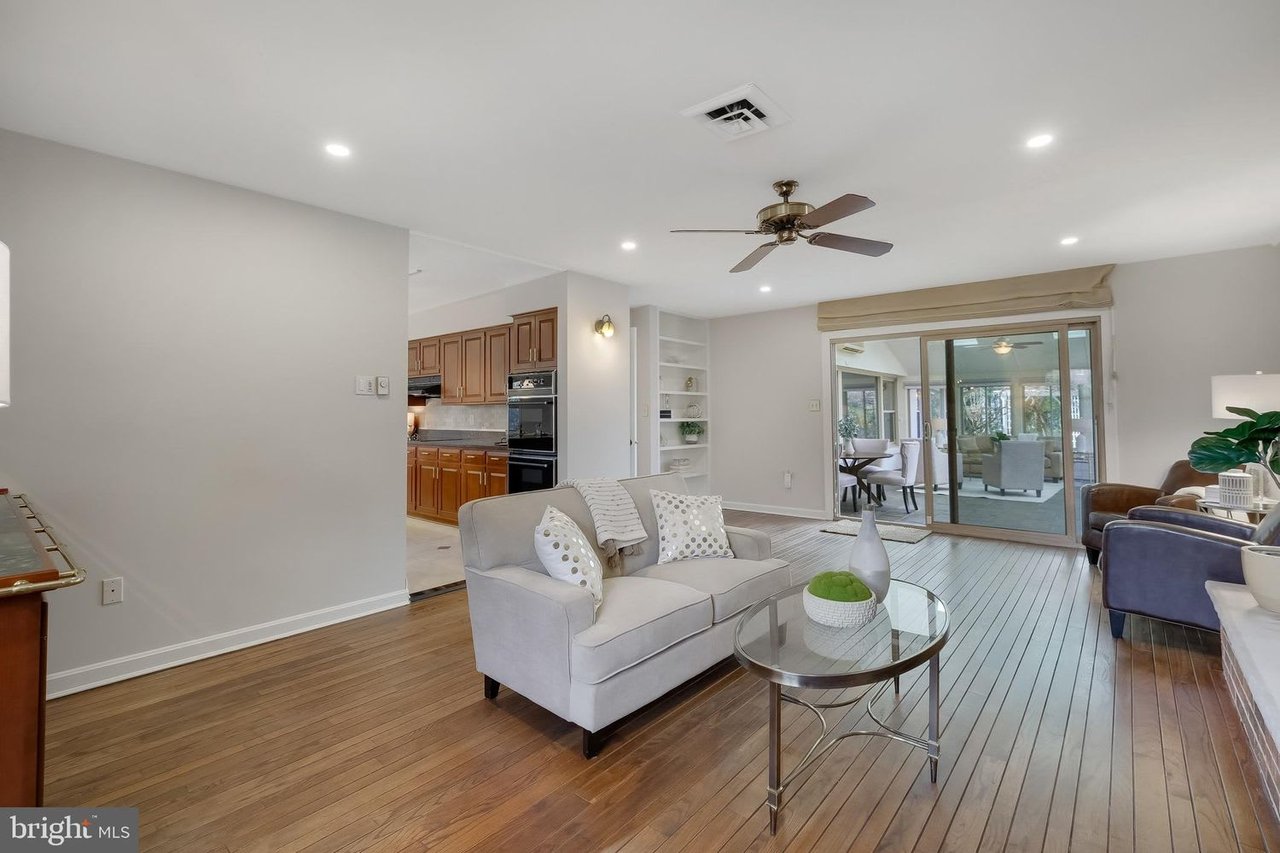 Living room with wood floors, a light sofa, and sliding glass doors to a sunroom.