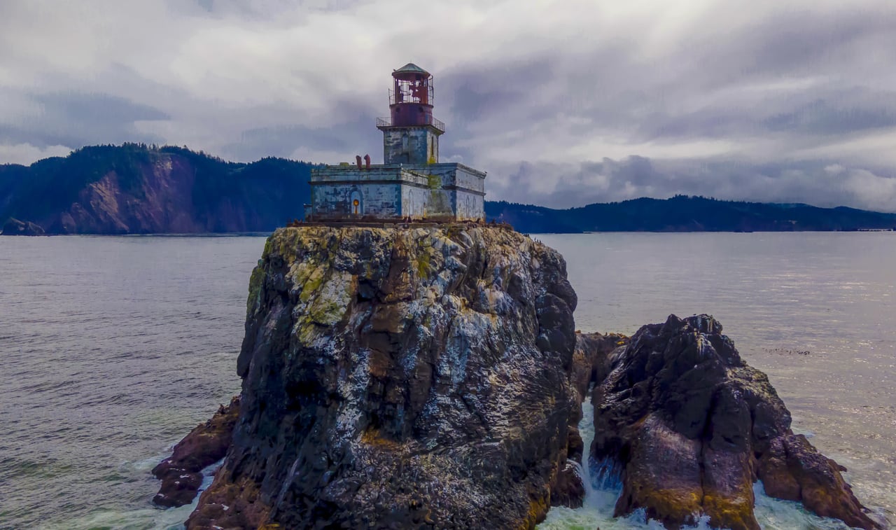 Aerial view of Tillamook lighthouse perched on a large rock with Cannon Beach in the background