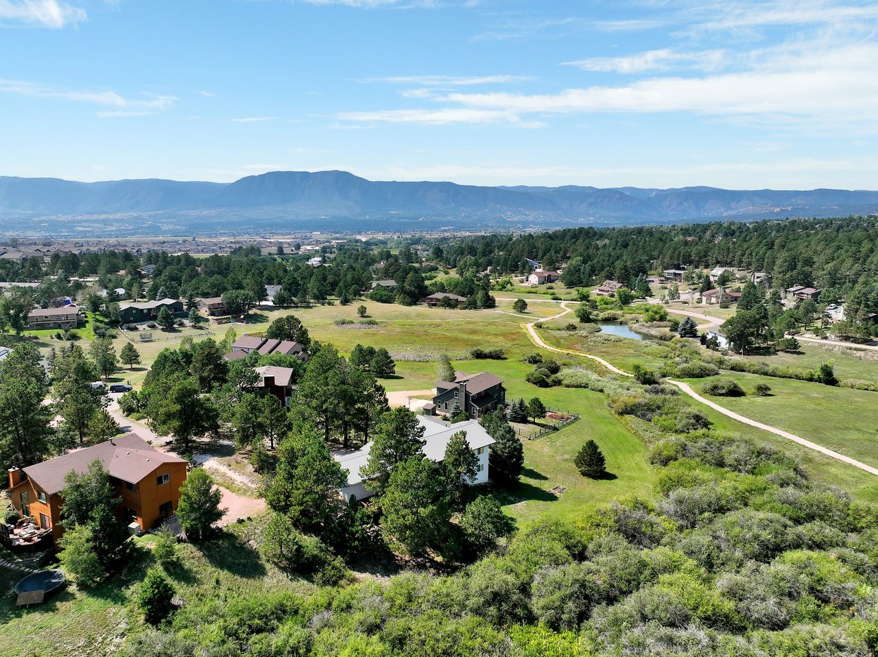 An aerial view of a suburban neighborhood nestled in a valley surrounded by mountains