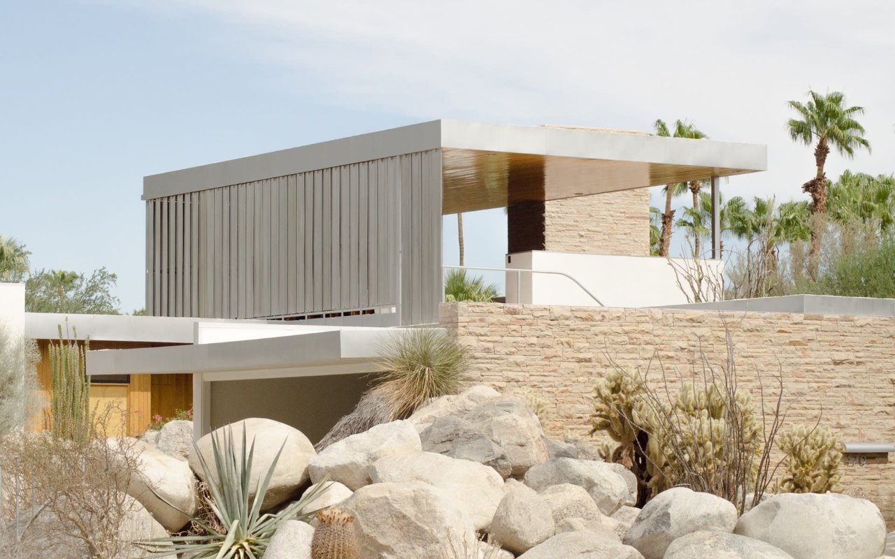 A modern house surrounded by rocks and palm trees