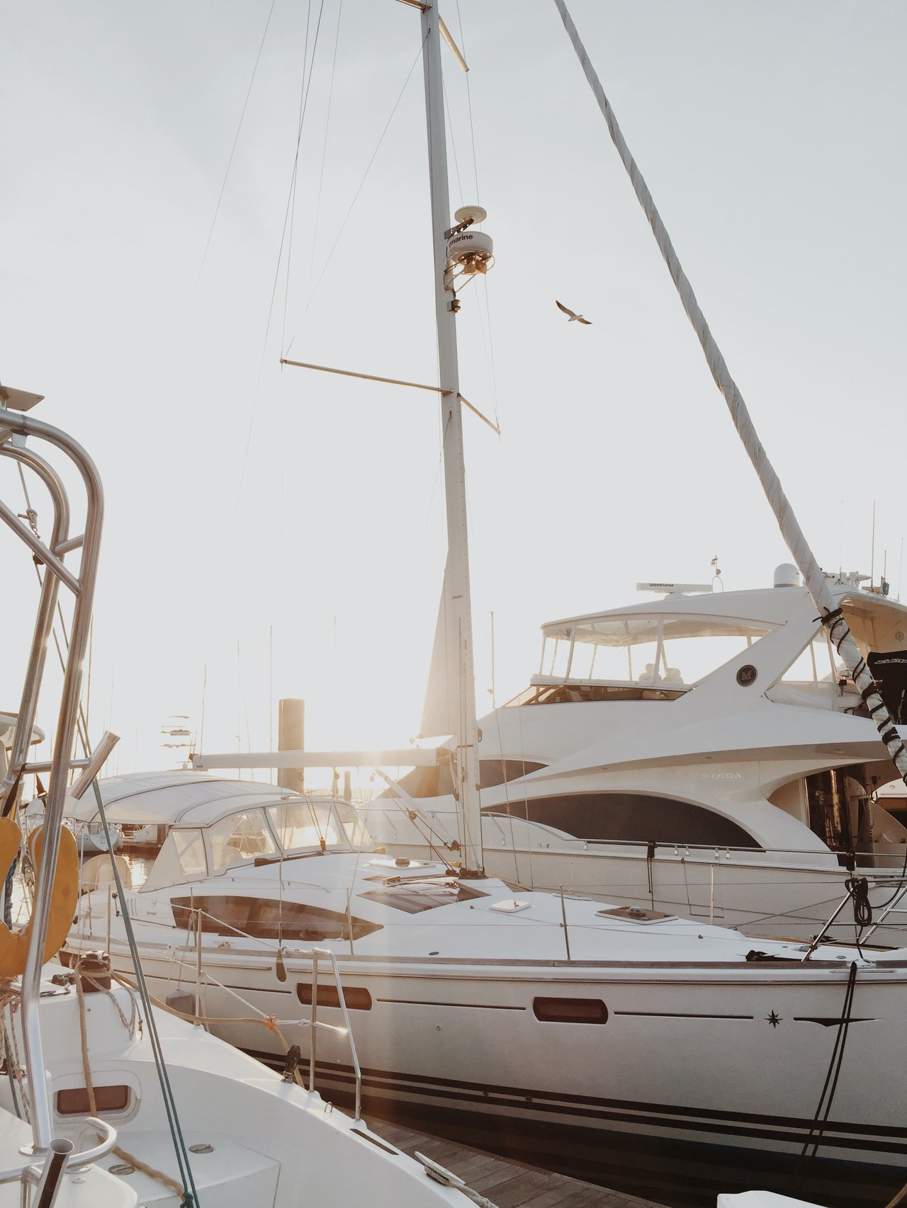  A close-up view of several boats docked in a marina under bright, hazy sunlight.
